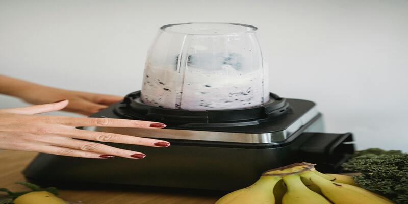 A hand with a glass cup on top of a blender AI-generated content may be incorrect.